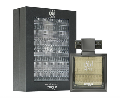 Zimaya Abadi square dark-framed bottle with pale gold patterned glass and wide geometric cap, beside its black box with silver ornamental panel on white.