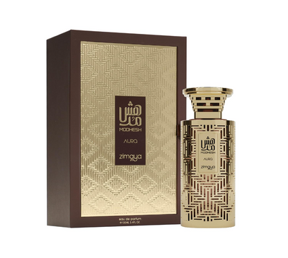 Zimaya Modhesh Aura cylindrical gold bottle with geometric cutout-style pattern and wide striped cap, beside its brown box with a textured gold panel on white.