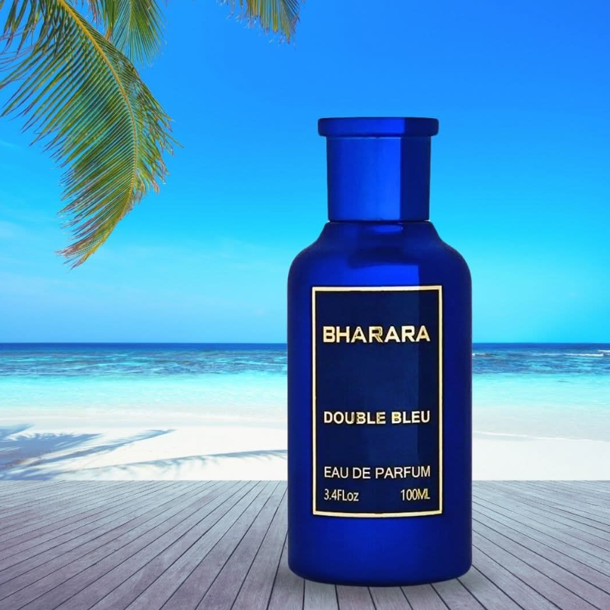 Cobalt-blue Bharara Double Bleu bottle with matching cap and a gold-bordered label on a wooden deck overlooking a turquoise sea, sandy beach and palm fronds.