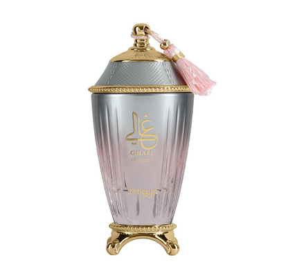 Zimaya Ghali Elegant ribbed silver-and-pink bottle with gold lettering, ornate gold footed base, textured domed silver cap with gold trim and pink tassel on white.