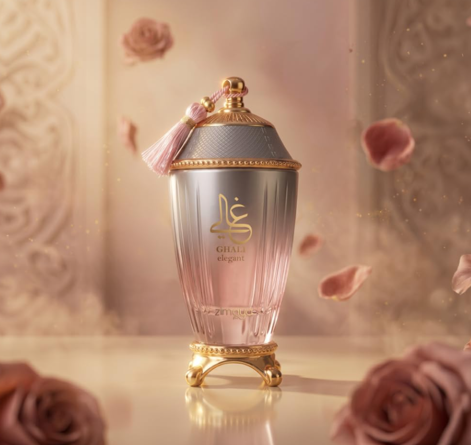 Zimaya Ghali Elegant pink-and-silver urn-shaped bottle with gold feet and pink tassel, on a reflective cream surface among roses and floating pink petals.