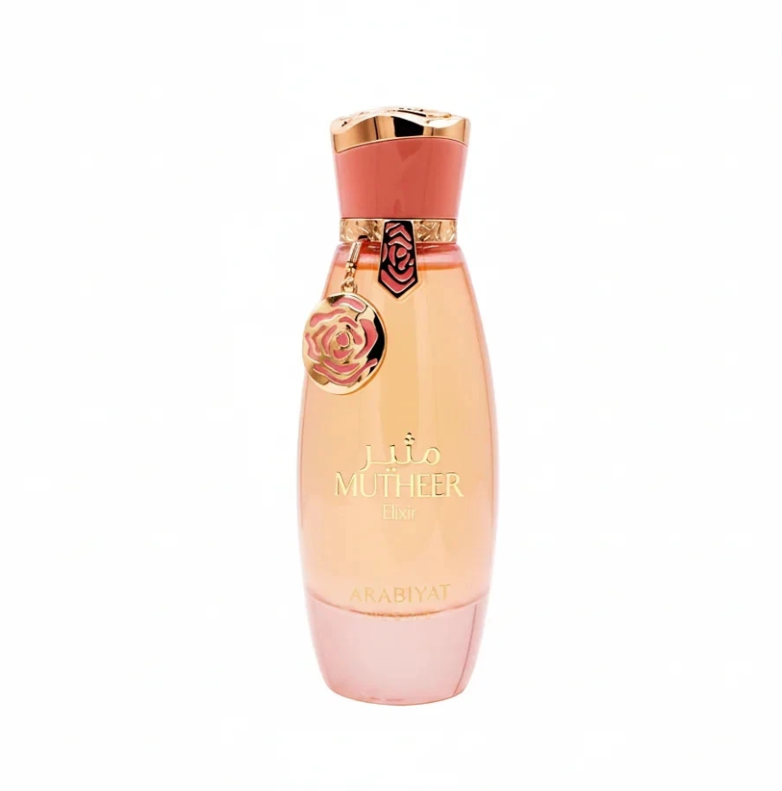Arabiyat Prestige Mutheer Elixir tapered peach perfume bottle with pink base, coral cap, gold trim and dangling round floral charm, isolated on white.