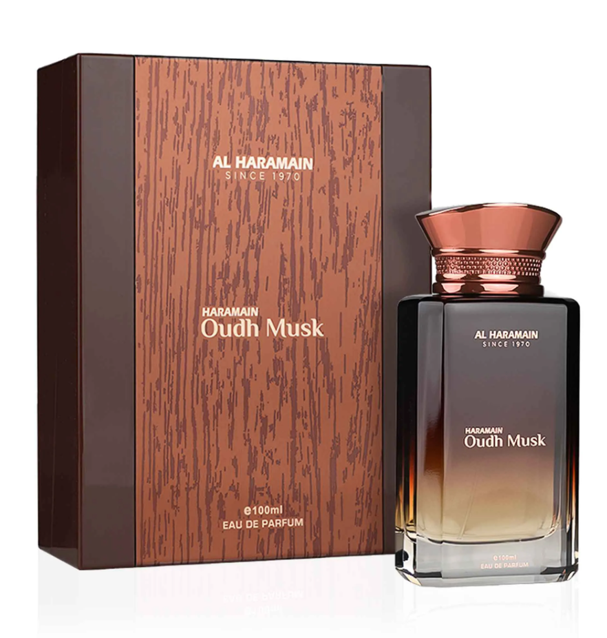 Al Haramain Oudh Musk dark-to-clear rectangular bottle with a copper-colored flared cap beside a brown woodgrain-patterned box on white.